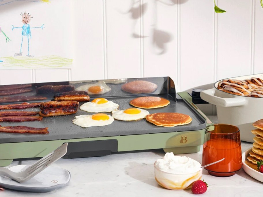 green electric skillet with eggs, bacon, and pancakes on top