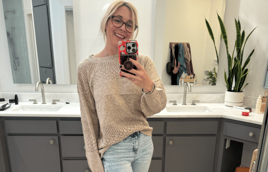 woman taking selfie in tan sweater
