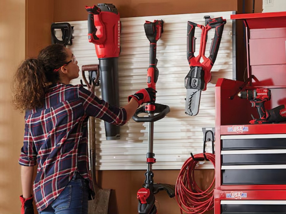 woman putting string trimmer up on wall