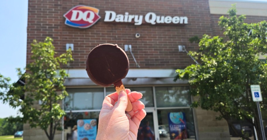 hand holding an ice cream bar with a Dairy Queen restaurant in the background