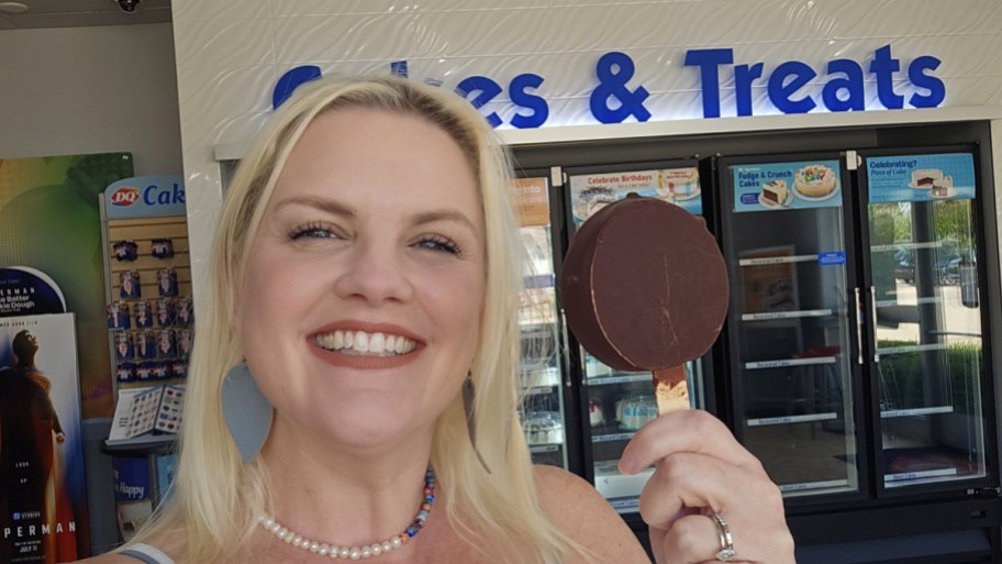 smiling woman holding a dq dilly bar inside the restaurant
