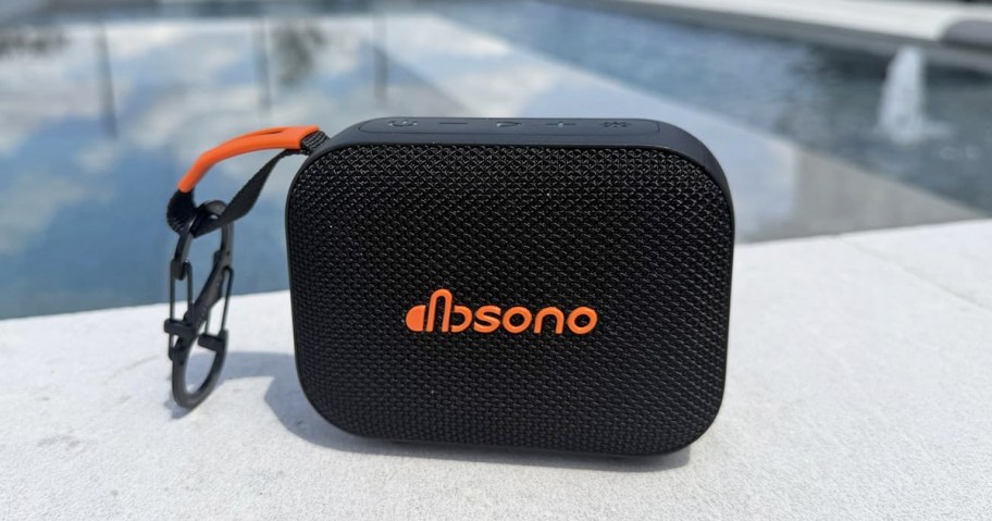 black bluetooth speaker next to a pool