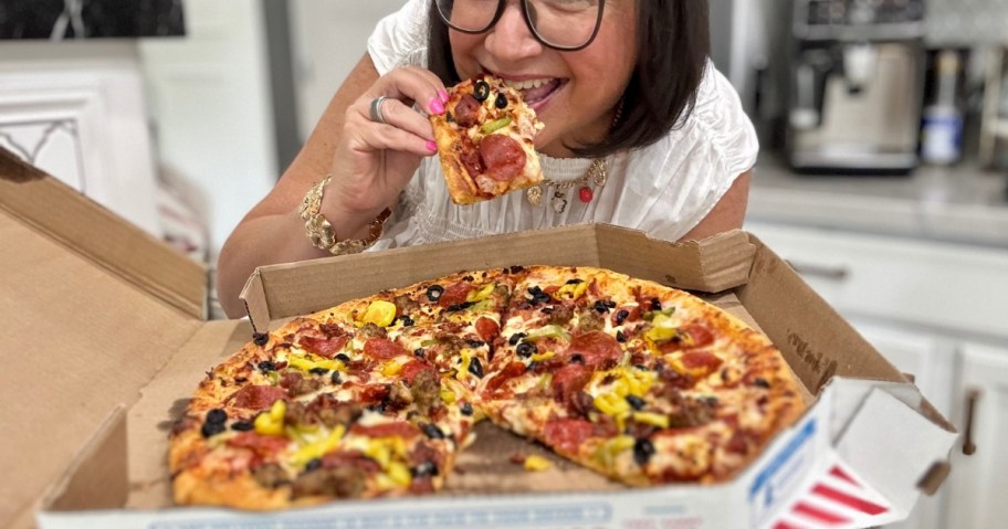 woman eating a pizza over a pizza box