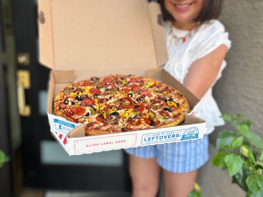 a woman holding a large open pizza box