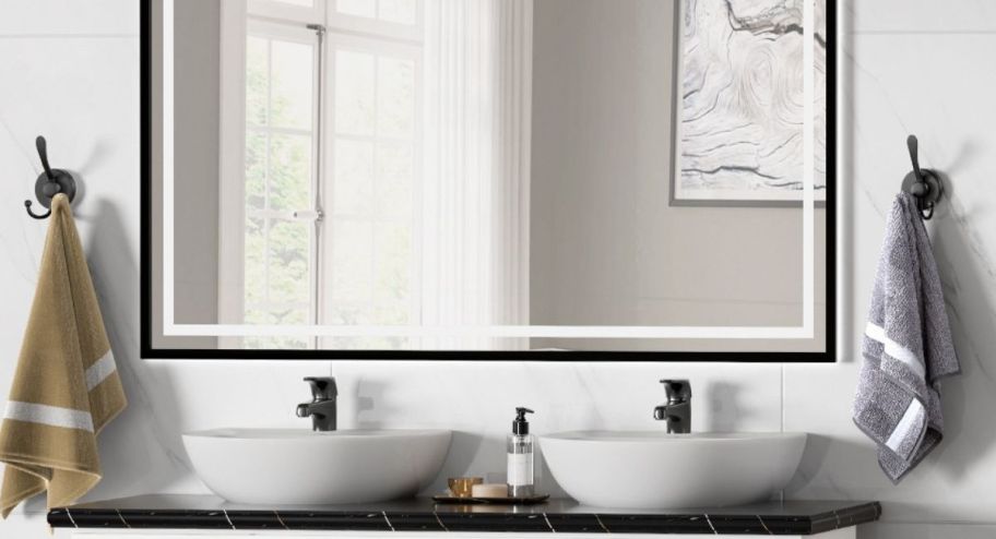 Bathroom displays hooks with towels and a large mirror