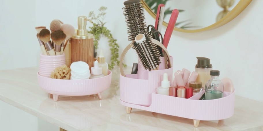 pink organizers full of beauty products on table