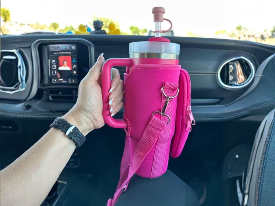 hand holding pink inmaya 30oz Water Bottle Tumbler Carrier Bag on tumbler in car