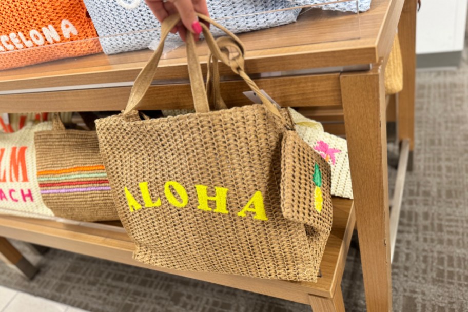 hand holding straw aloha bag and wristlet in store