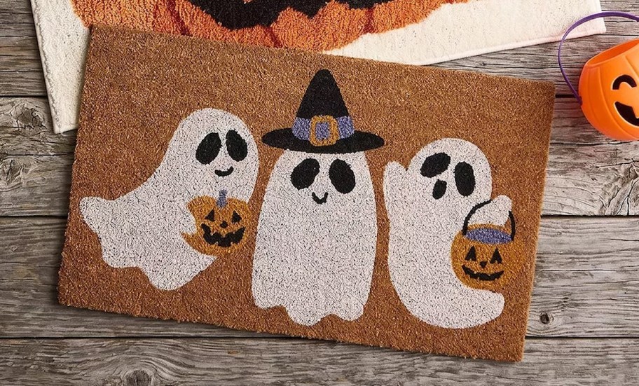 three cute ghosts on doormat laying on wood planks