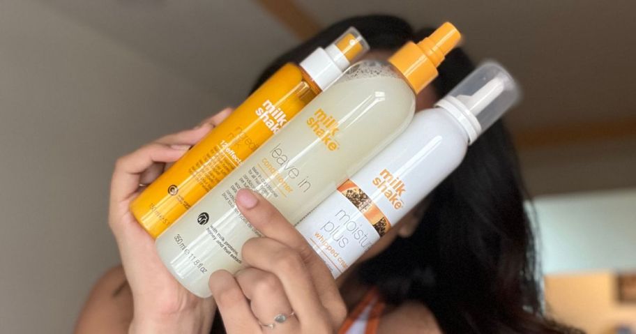 woman holding three milk shake hair products