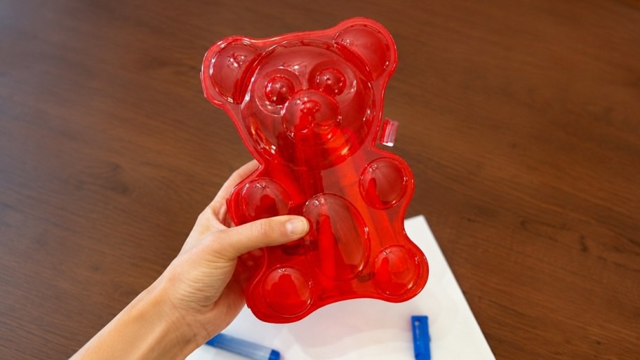 a hand holding a red gummy bear pencil case