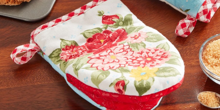 red and white floral oven mitt on table