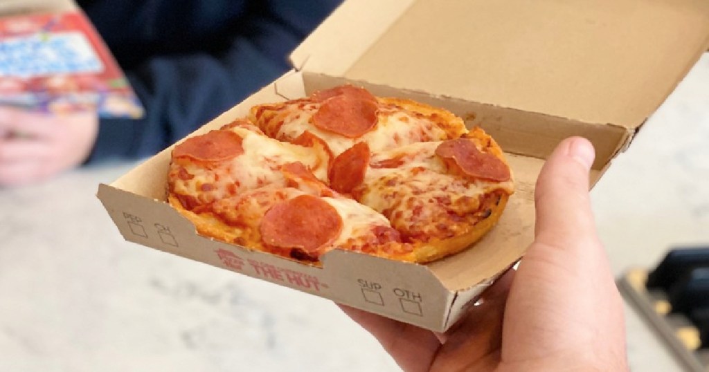 hand holding a box with a Pizza Hut personal pan pizza in it