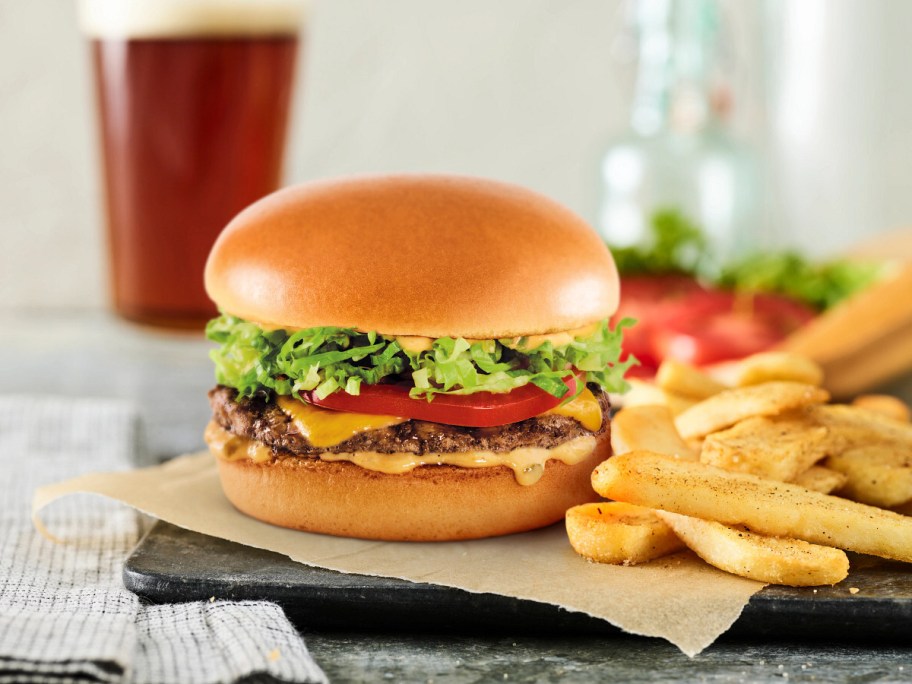 burger on parchment paper next to fries