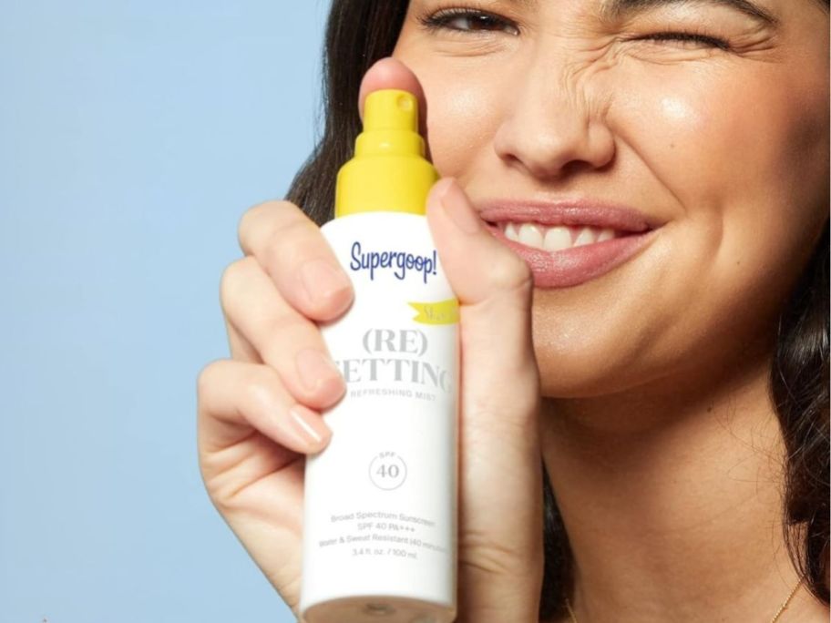 woman spraying supergoop! spray