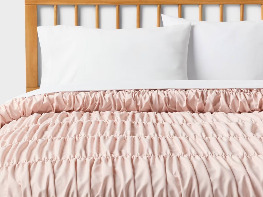 pink comforter on bed with white pillows 