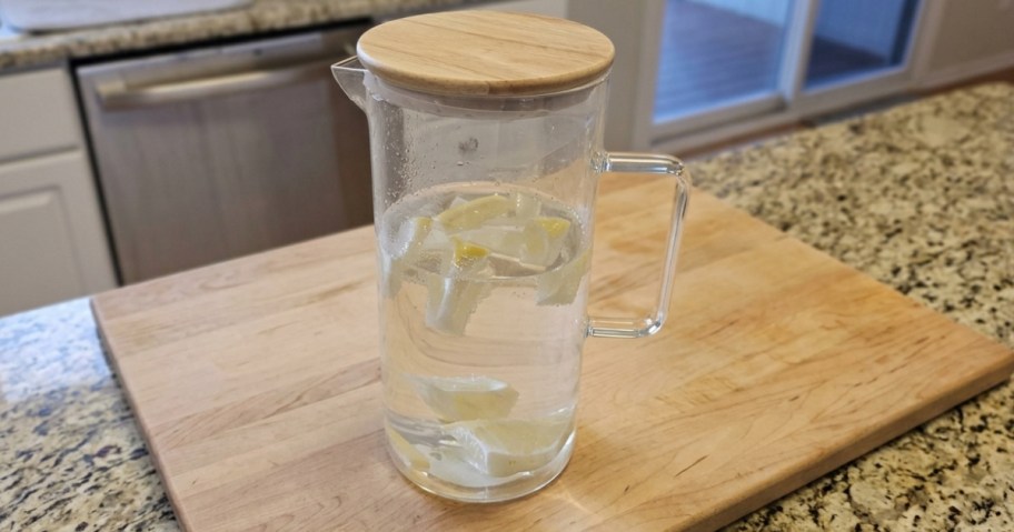 glass pitcher with wood lid on wooden cutting board in kitchen