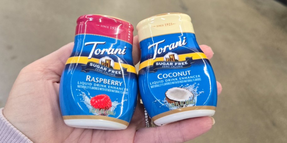 hand holding coconut and raspberry torani drink enhancers