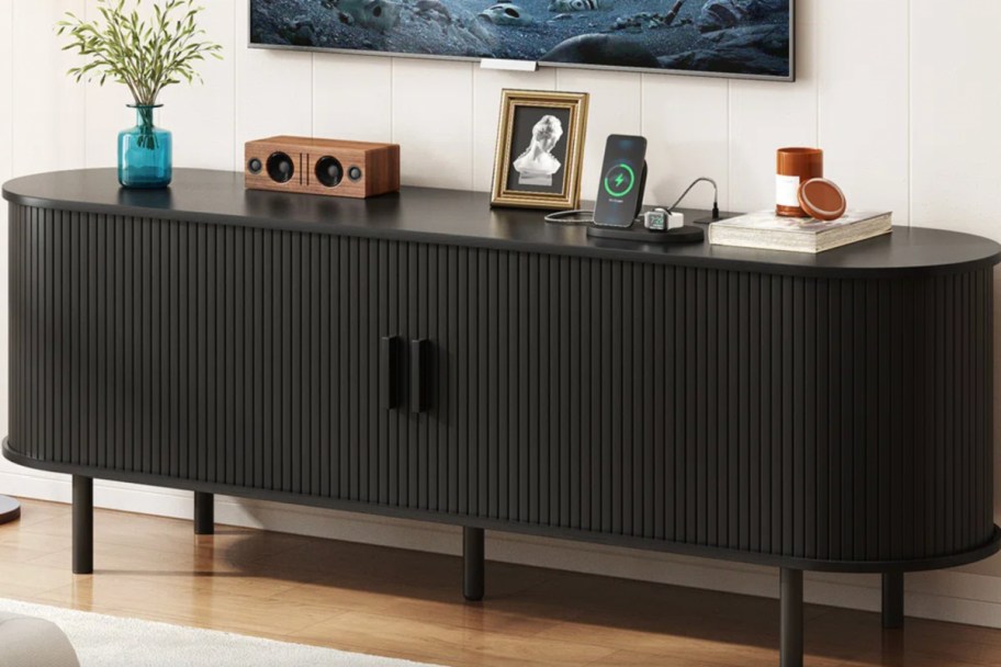 black ribbed wooden tv stand with decor on top