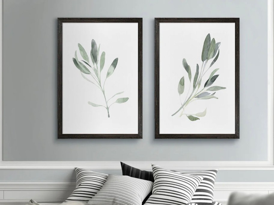 white wall art with green plants hanginga bove couch 