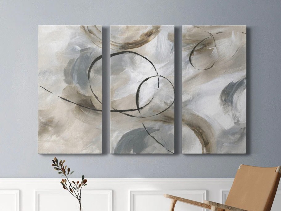 three gray, teal, abstract canvas prints hanging on wall 