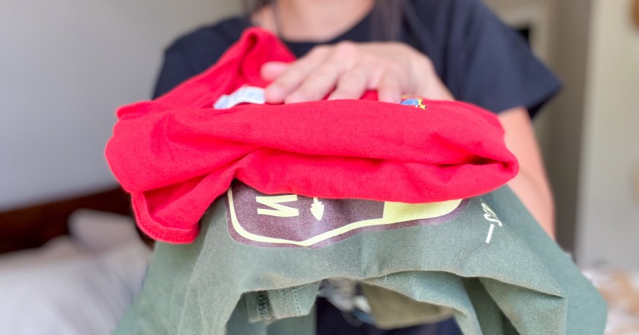 woman holding 2 folded graphic tees