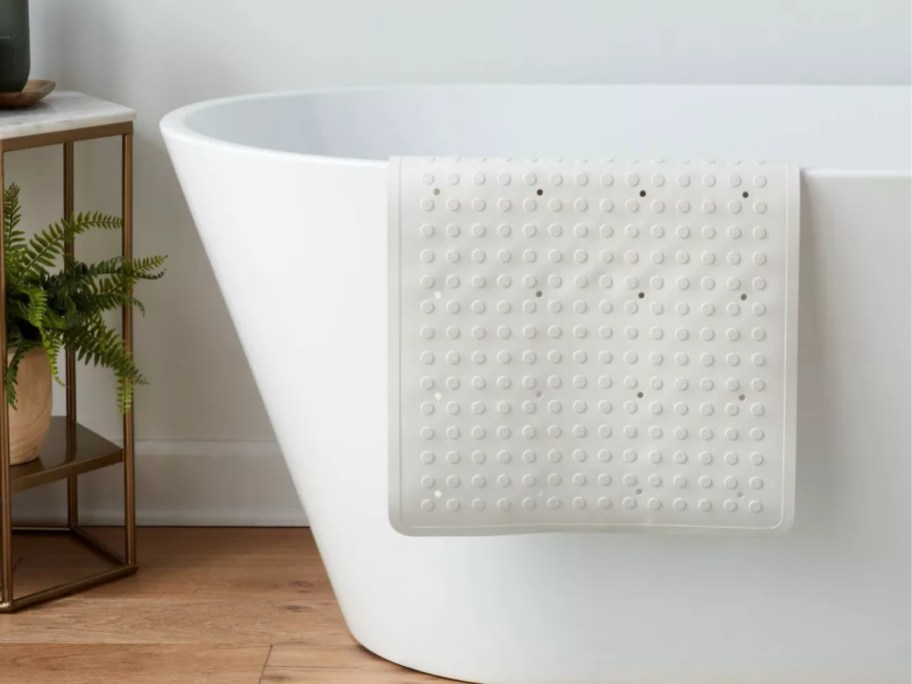 a white bath mat on the side of a tub