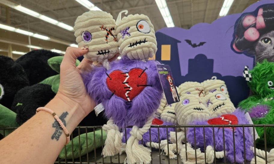 a woman's hand holding a two headed mummy monster rope pet toy