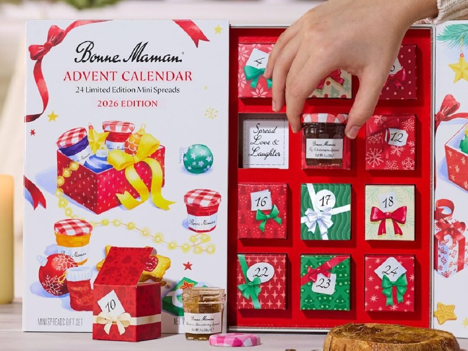 A hand opening a compartment in the 2026 Bonne Maman Advent Calendar to reveal a mini jam jar.