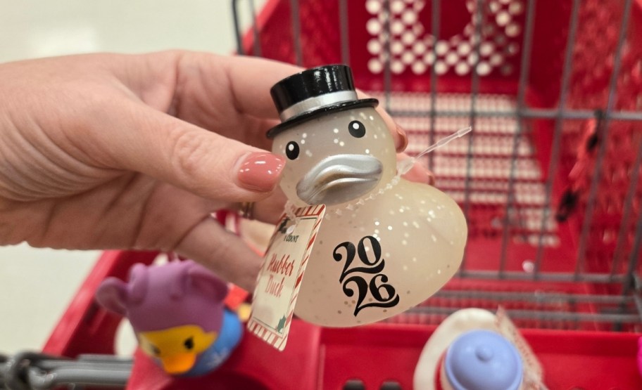 a womans hand holding a new years even themed rubber duck wearing a top hat
