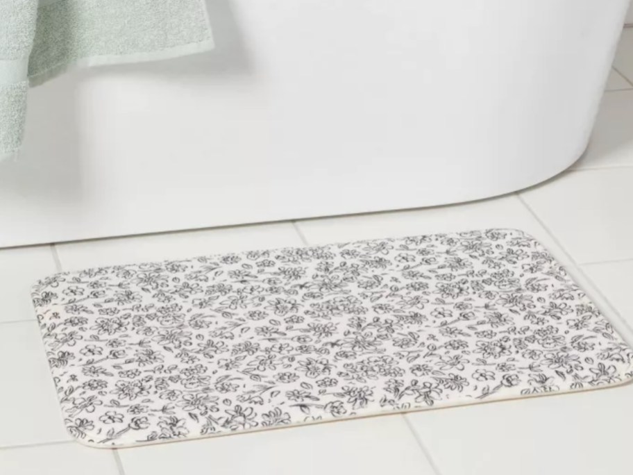a floral black and white bath rug by a tub