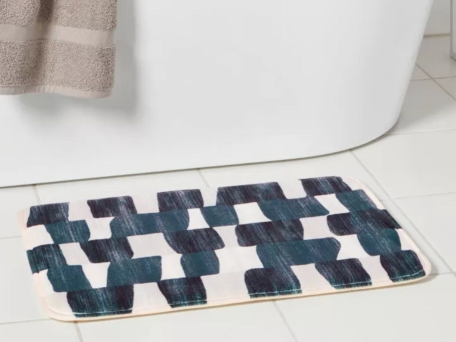 a blue and white pattern bath rug by a tub