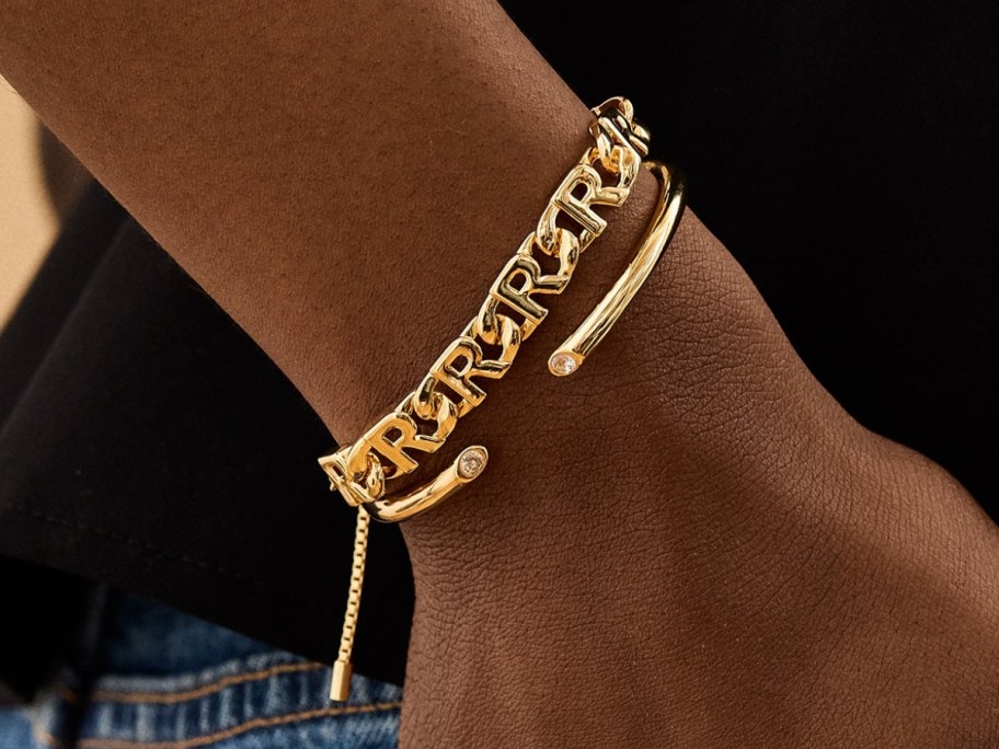person's wrist with an initial bracelet and cuff bracelet
