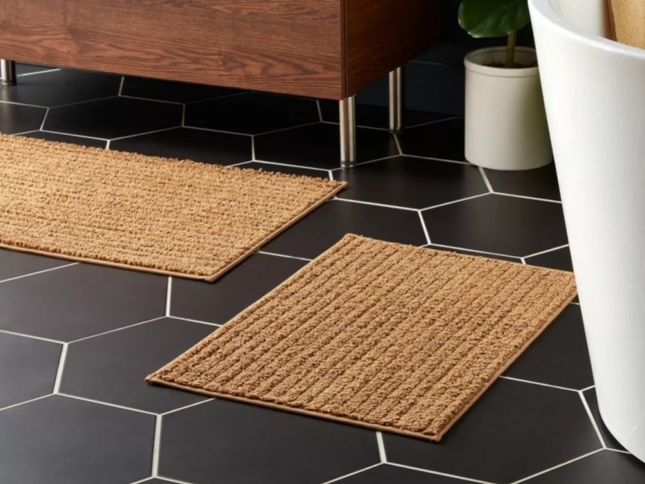 two brownish tan bath rugs on a bathroom floor