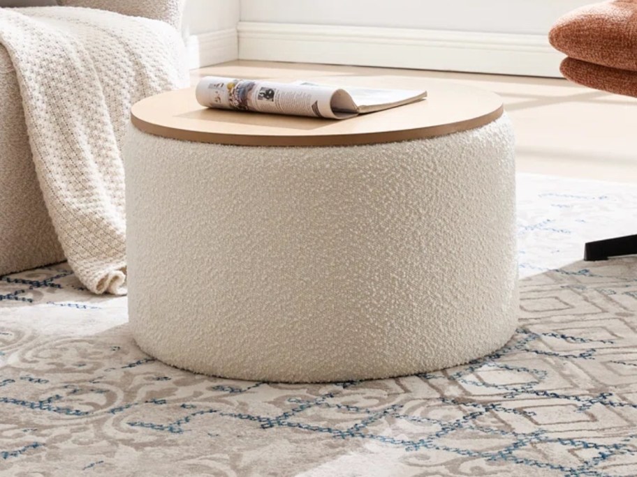 an upholstered round storage ottoman with a wood top in a living room