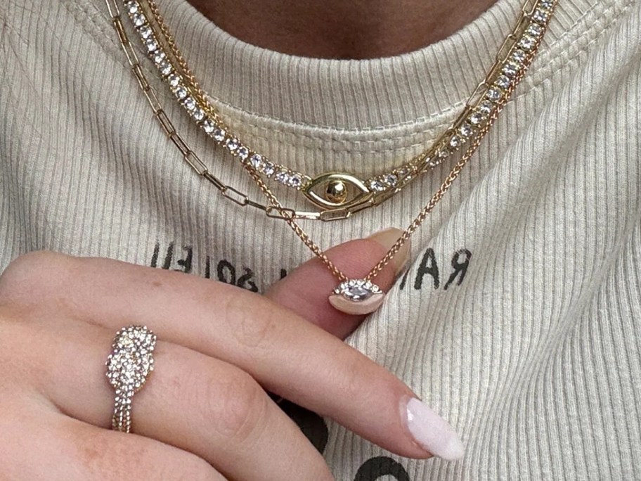 woman wearing several necklaces, with her hand on one of them