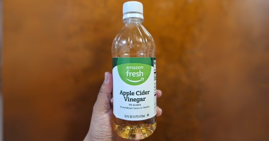 person holding amazon fresh apple cider vinegar 16oz bottle
