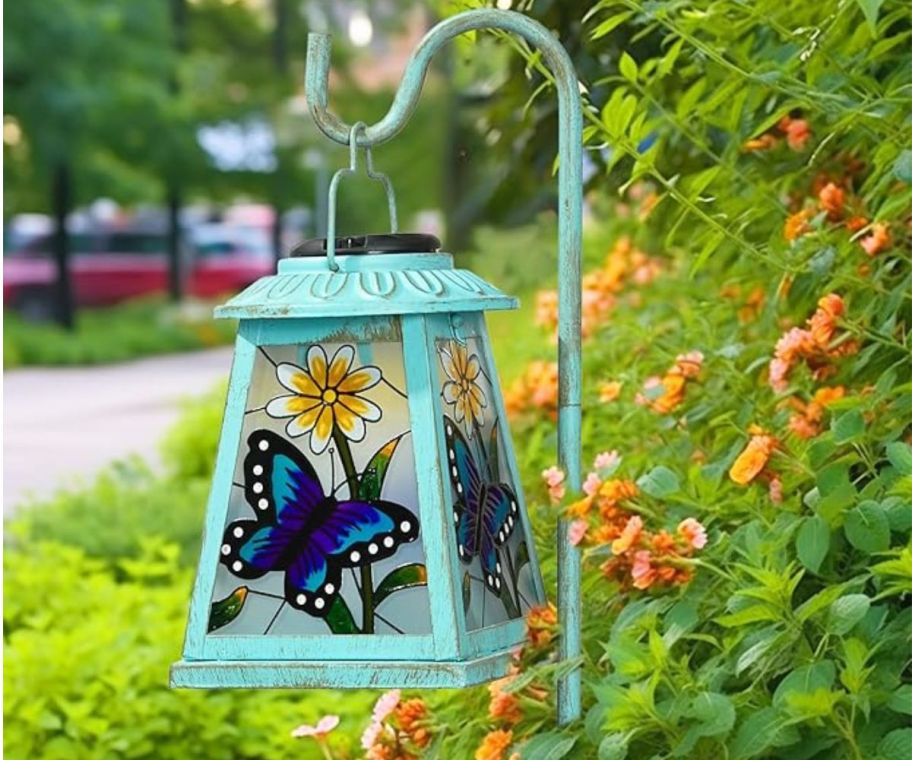 A lantern in a garden with a stained-glass picture of a butterfly