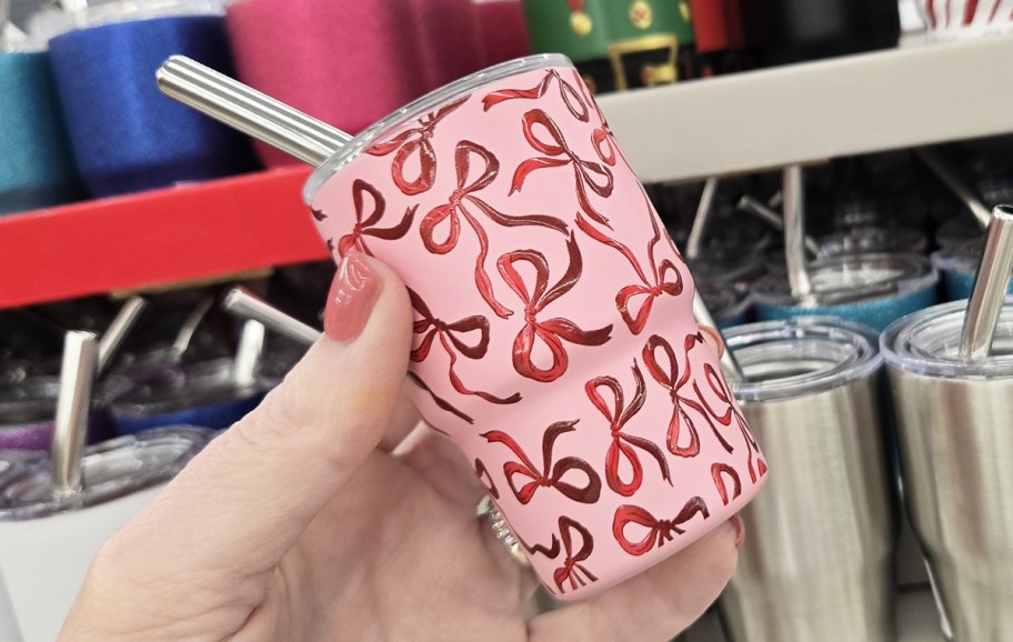 hand holding a pink mini tumbler with red bows print