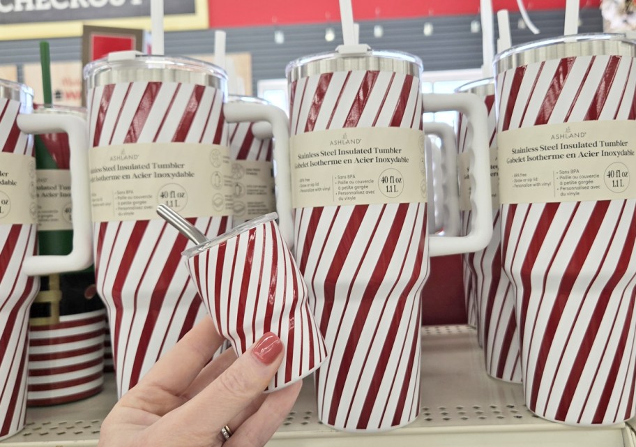 hand holding a mini peppermint stick tumbler next to larger matching tumblers on store shelf