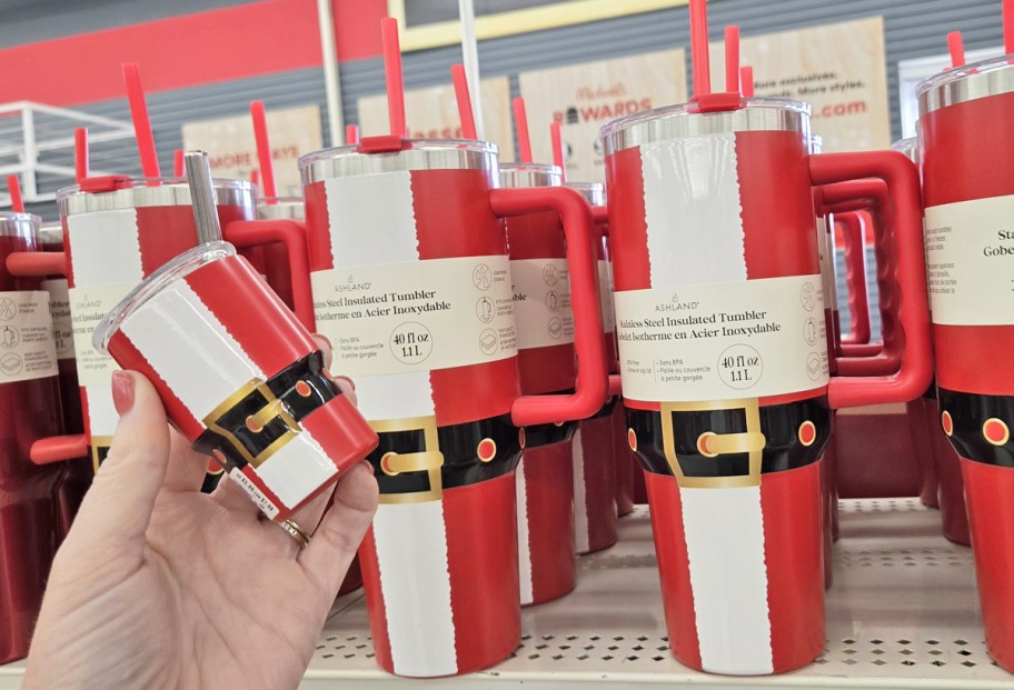 hand holding a mini red and white santa tumbler next to larger matching tumblers on store shelf