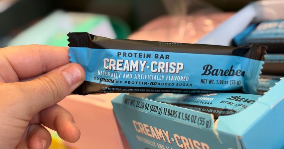 A person holding a Barebells Protein Bar in blue wrapping