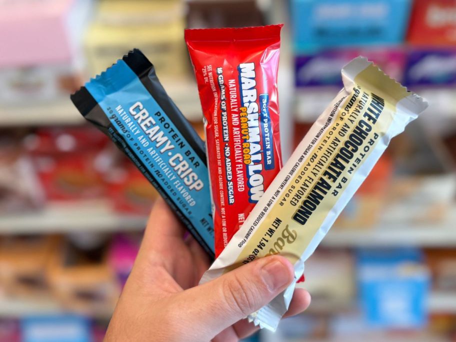 A person holding three Barebells Protein Bars