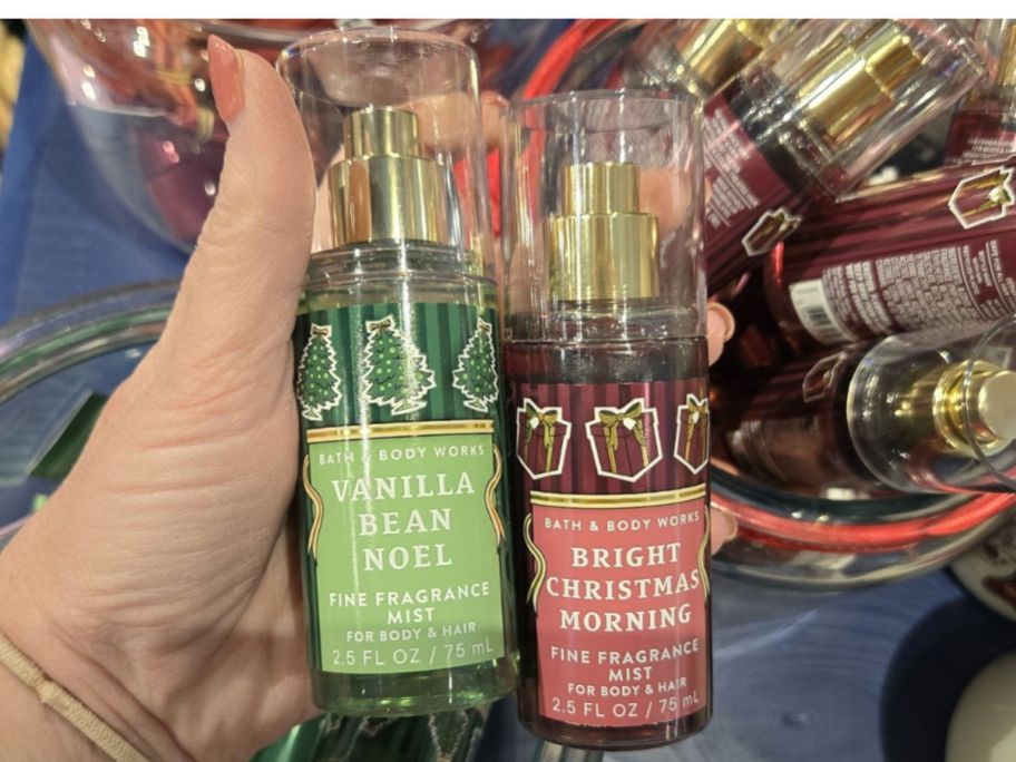 Hand holding Two Bath & Body Works Body Sprays