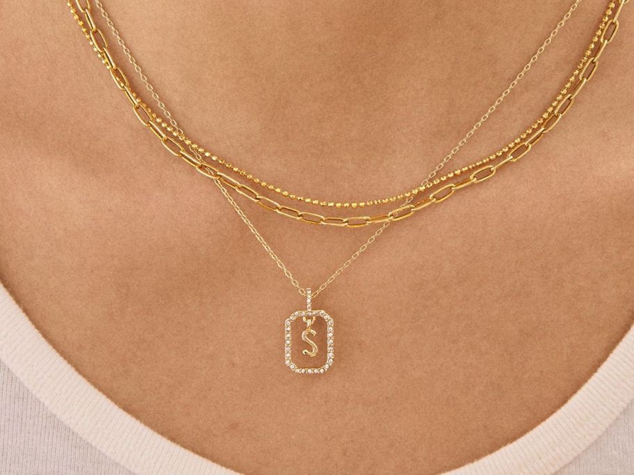 BaubleBar Alicia Initial Necklace layered with other piece on a womans neck