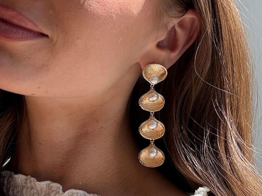 woman wearing BaubleBar Calypso Seashell Earrings with a wwhite top