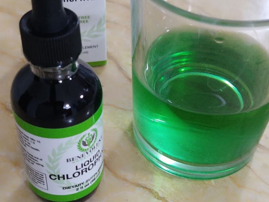 A bottle of Benevolent Chlorophyll and a glass of green colored water