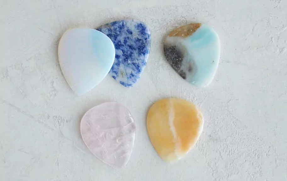 Different colors of five guitar picks laying on the table 