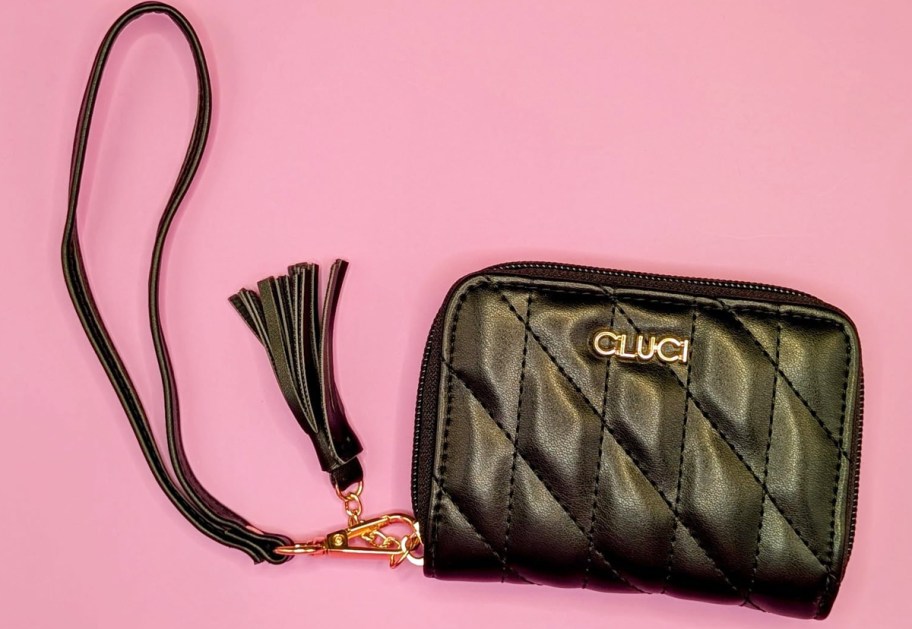 black faux leather wristlet on a pink background