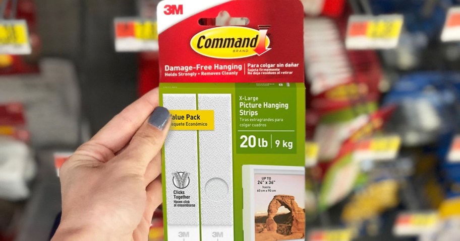 hand holding a pack of Command Picture Hanging Strips in store